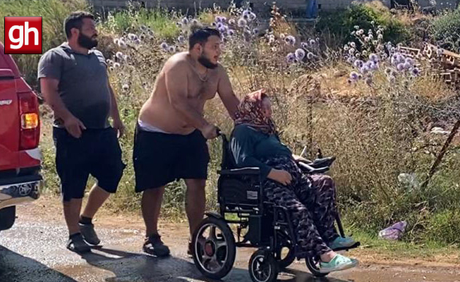 Aksu'da evine yaklaşan alevlerden kurtarılan kadın tekerlekli sandalyeyle bölgeden uzaklaştırıldı